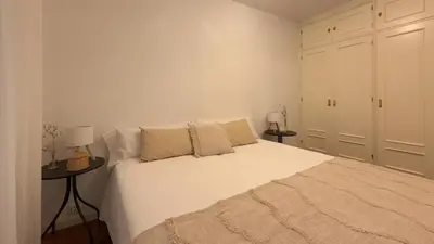a bedroom with a large white bed with two tables at VIVIENDA OLGA, piso tranquilo con parking a 10 min de Santiago in Sigüeiro