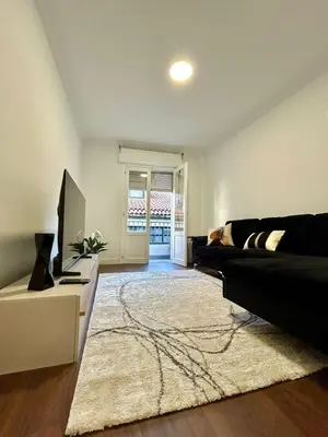 a living room with a black couch and a television at Apartamento en el casco historico in Ourense