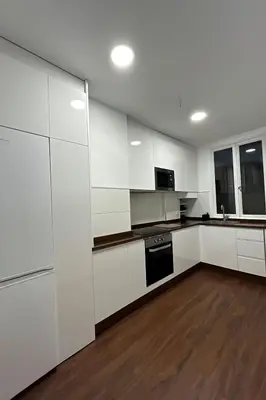 a white kitchen with white cabinets and a wooden floor at Apartamento en el casco historico in Ourense