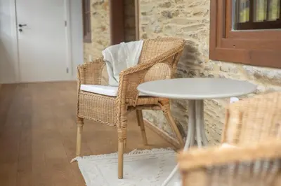 a wicker chair and a table in a room at Apartamentos Rurales Casa Carlota in Vegadeo