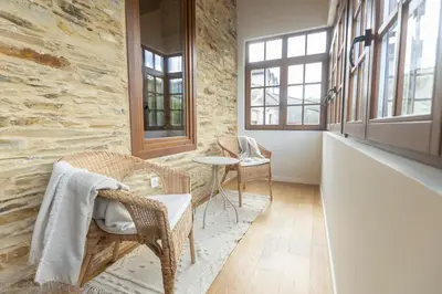 a hallway with chairs and a table and windows at Apartamentos Rurales Casa Carlota in Vegadeo