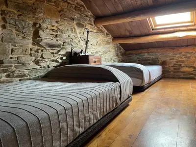 two beds in a room with a stone wall at Casa El Reposo in Barreiros