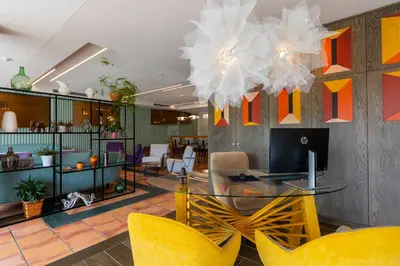 a lobby with a glass table and yellow chairs at Hotel O Cabazo in Ribadeo