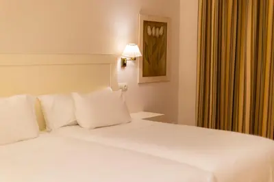 a white bed with white pillows in a room at Hotel O Cabazo in Ribadeo