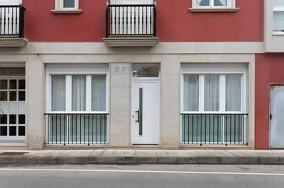 a red building with a white door and windows at Nataly,s House in Tapia de Casariego