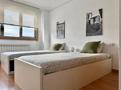 two beds in a white room with two windows at A Gandarela in Ribadavia