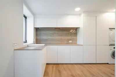 a kitchen with white cabinets and a wooden floor at Relax in Santiago de Compostela in Vedra