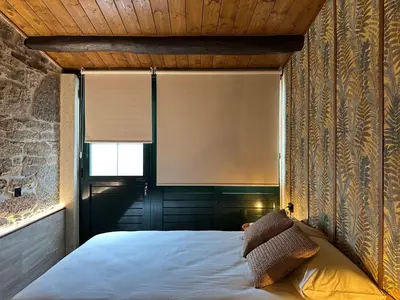 a bedroom with a bed with a window and a window shade at Casa Arxemil in Sarria