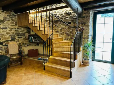 a wooden staircase in a room with a stone wall at Casa Arxemil in Sarria
