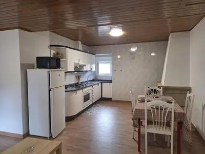 a kitchen with a table and a white refrigerator at Casa María in Baltar