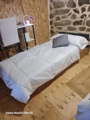a white bed with a pillow and a table at Oira House Jacuzzi Casa en Ourense in Ourense