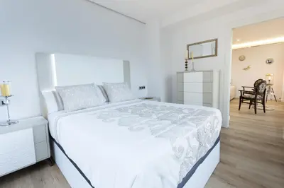 a white bedroom with a large bed and a dining room at GemAn1 in Monforte de Lemos