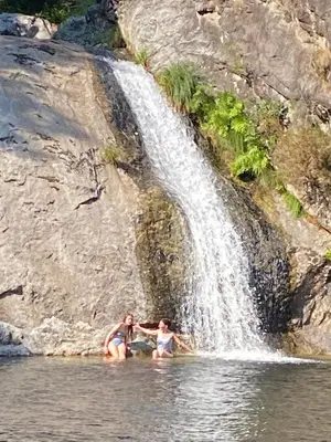 two women in the water in front of a waterfall at Casa de Piedra Vistas & Relax
