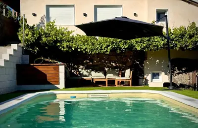 an umbrella over a swimming pool in a yard at Wine Lodge Ribeira Sacra in Carracedo