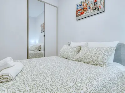 a white bedroom with a bed and a mirror at Aida's Apartments in Puentes de García Rodríguez