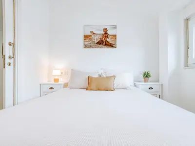 a white bedroom with a large white bed at Aida's Apartments in Puentes de García Rodríguez