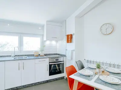 a kitchen with a table and a clock on the wall at Aida's Apartments in Puentes de García Rodríguez
