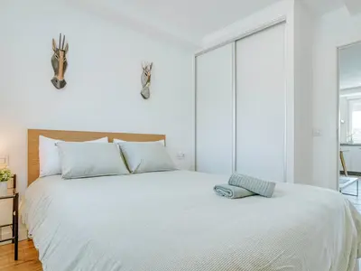 a white bedroom with a large bed with white sheets at Aida's Apartments in Puentes de García Rodríguez