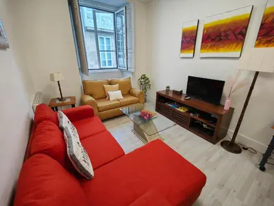 a living room with a red couch and a television at Rua Nova Apartment 28, 3 Dormitorios, WIFI, PS4 y Netflix, a 200m Catedral in Santiago de Compostela