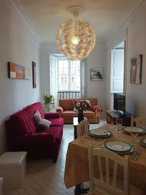 a living room with a table and a chandelier at Rua Nova Apartment 28, 3 Dormitorios, WIFI, PS4 y Netflix, a 200m Catedral in Santiago de Compostela