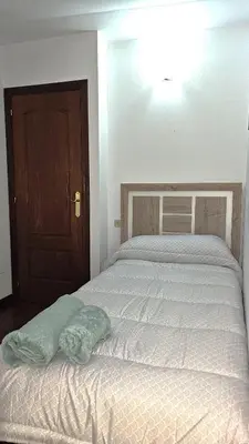 a bed in a bedroom with a wooden door at Garcia Prieto Vivienda in Santiago de Compostela