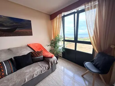 a living room with a couch and a large window at Amanecer en Playa de LLás in Foz