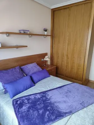 a bedroom with a large bed with purple pillows at Amanecer en Playa de LLás in Foz