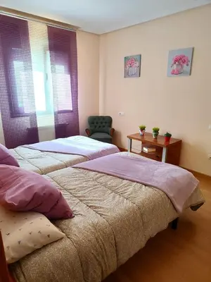 a bedroom with two beds and a chair at Amanecer en Playa de LLás in Foz