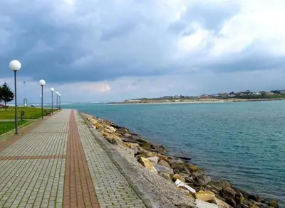 a brick walkway next to the water with street lights at Amanecer en Playa de LLás in Foz