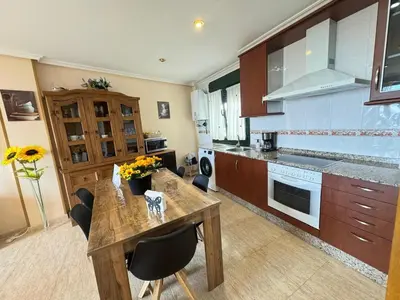 a kitchen with a wooden table and some chairs at Amanecer en Playa de LLás in Foz