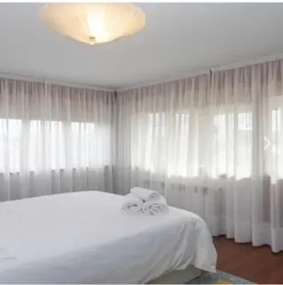 a bedroom with a white bed with white curtains at apartamento 1 matrimonial con terraza acristalada in Tapia de Casariego