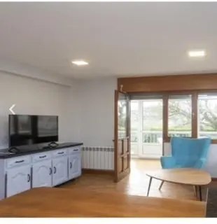 a living room with a tv and a blue chair at apartamento 1 matrimonial con terraza acristalada in Tapia de Casariego
