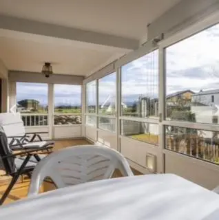 a room with a bed and chairs on a balcony at apartamento 1 matrimonial con terraza acristalada in Tapia de Casariego