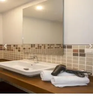 a bathroom with a sink and a mirror and towels at apartamento 1 matrimonial con terraza acristalada in Tapia de Casariego