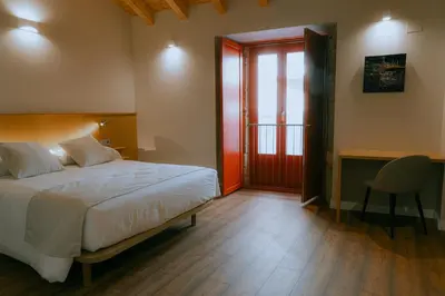 a bedroom with a large white bed and a chair at Hotel Recanto do Avia in Ribadavia