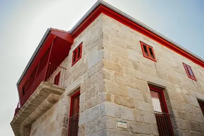 a brick building with red windows on the side of it at Hotel Recanto do Avia in Ribadavia