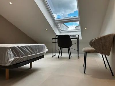 a attic bedroom with a bed and two chairs at Apartamento Lujo Casco Histórico in Santiago de Compostela