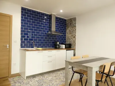 a kitchen with a table and a blue tile wall at Monqar Leandro in Foz