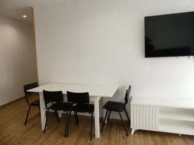a white table with chairs and a tv on a wall at Monqar Leandro in Foz