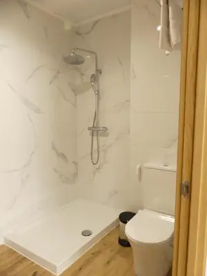 a white bathroom with a shower and a toilet at Monqar Leandro in Foz