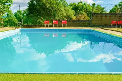 a swimming pool with blue water and red chairs at La Casa del Monte in Ocero