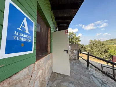 a sign on the side of a green building with a door at Albergue Turístico El Campelín in Ocero