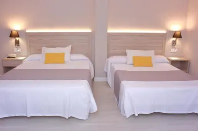 two beds in a hotel room with white and yellow pillows at Hotel Villa de Verín in Verín