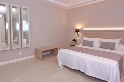 a white bedroom with a large bed and a table at Hotel Villa de Verín in Verín