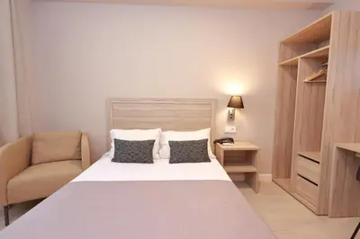 a small bedroom with a bed and a chair at Hotel Villa de Verín in Verín