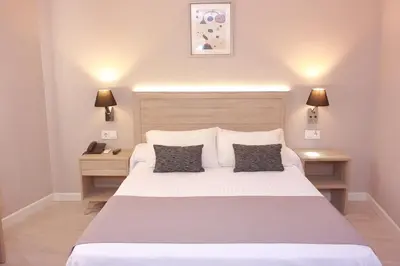 a bedroom with a large white bed with two lamps at Hotel Villa de Verín in Verín