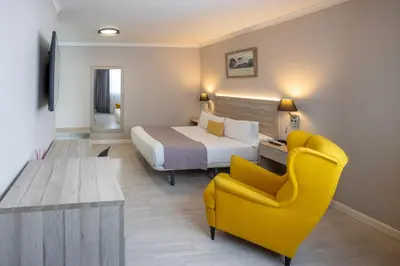 a hotel room with a bed and a yellow chair at Hotel Villa de Verín in Verín