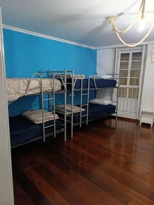 a room with three bunk beds and a blue wall at Kilómetro99 in Lugo