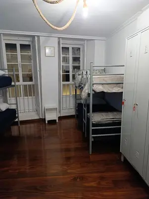 a room with two bunk beds and wooden floors at Kilómetro99 in Lugo