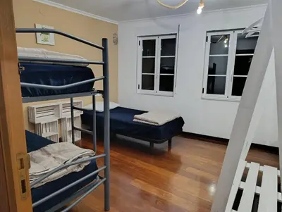 a room with three bunk beds and a bench at Kilómetro99 in Lugo